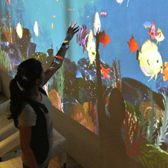 Girl plays touch-based aquarium-themed TouchMagix interactive wall