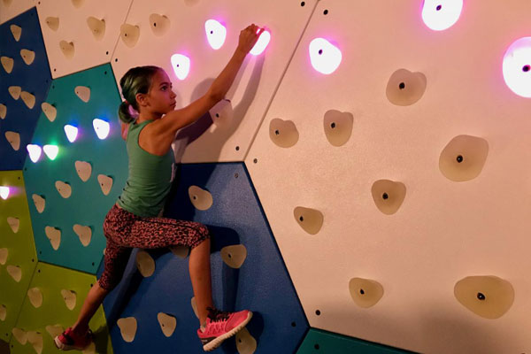 Young girl active with GlowHolds climbing wall system
