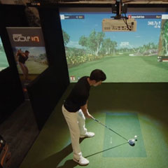 Young man playing Golfin IDRA 2 golf simulator