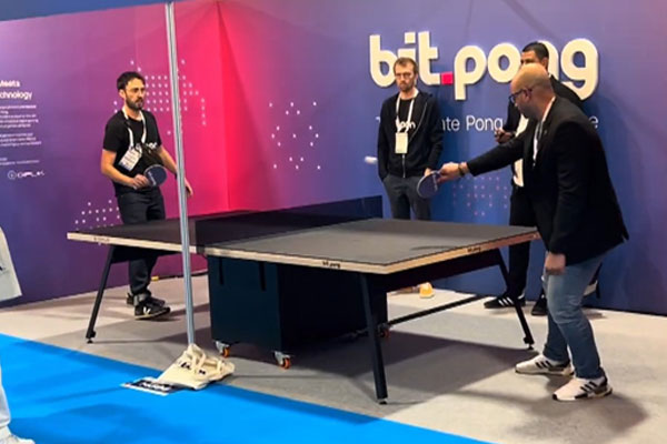 Attendees enjoying a match on Bit-Pong during a lively trade show