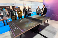 Participants competing on Bit-Pong digital ping pong while spectators watching the interactive action