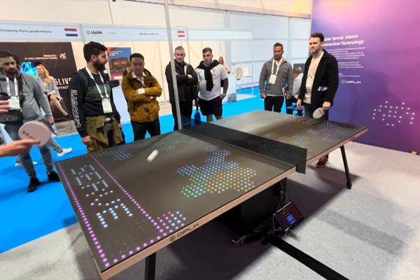 Two players going head-to-head on Bit-Pong as onlookers gather to watch the interactive competition