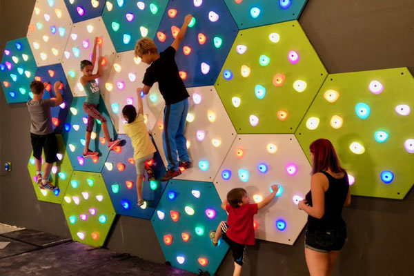 Kids playing on GlowHolds illuminated climbing wall system
