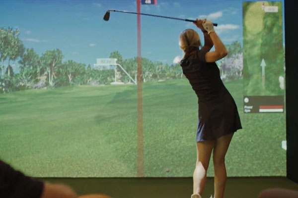 Young woman hitting a golf ball at an event