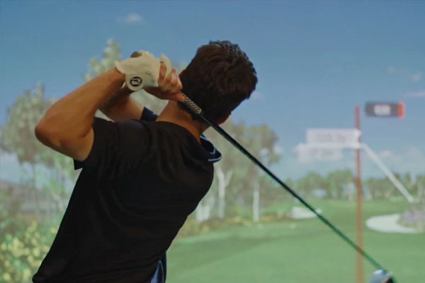 Young man playing a golf simulator game